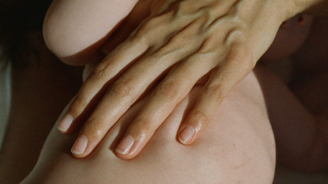 Mano de mamá sobre barriga de bebé dormido